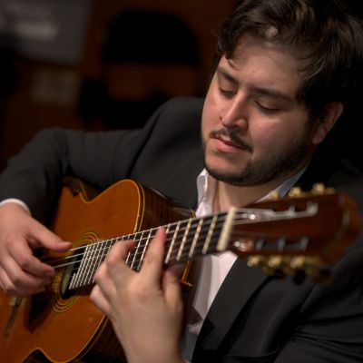 Man playing classical guitar with focus.