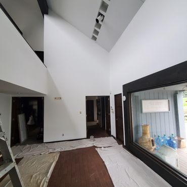 Interior of a house with white walls and brown tiled floor covered with protective sheets.