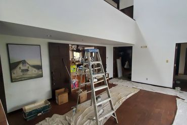 Interior room undergoing renovation with ladder and drop cloths.