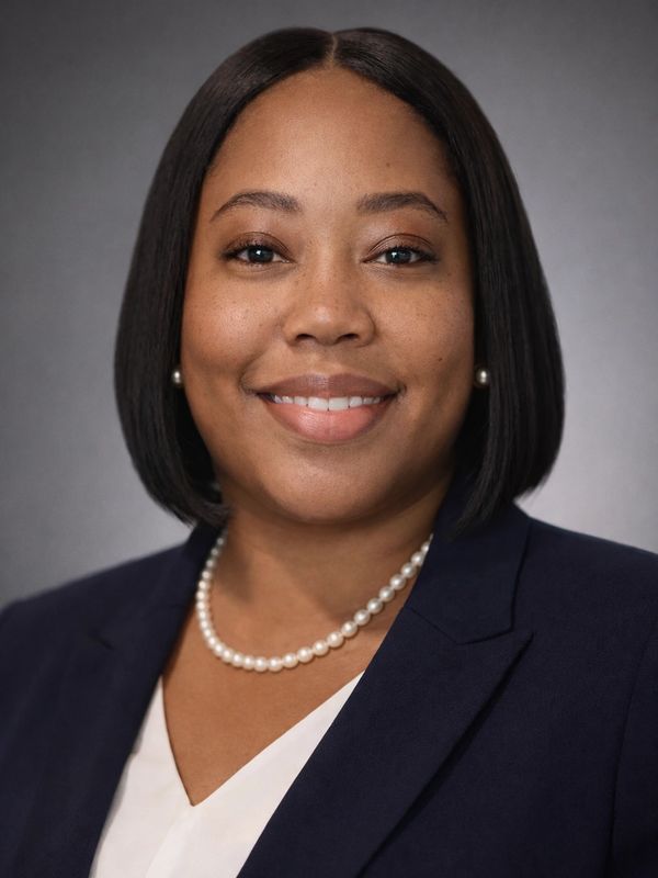 Professional woman with pearl necklace and navy blazer smiling.