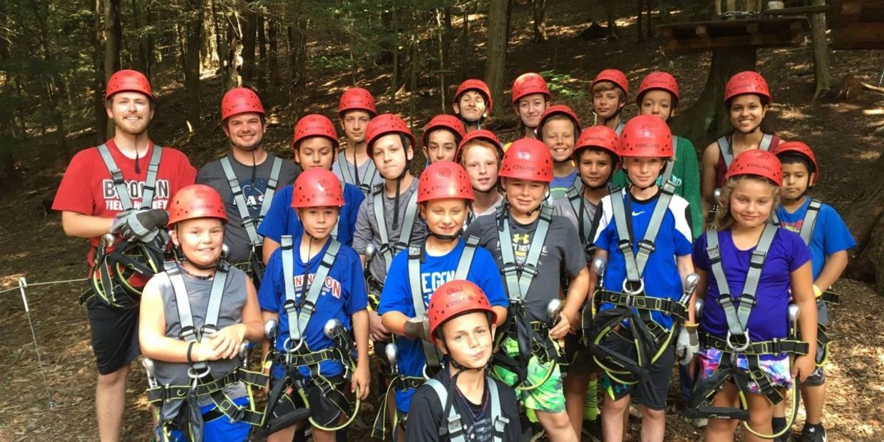 A group of kids and two adults in safety gear ready for an outdoor adventure.