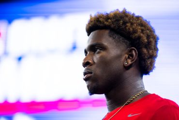 Profile of a young man with styled hair in a red shirt.