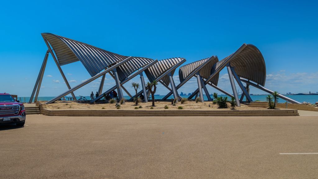 Modern metal structure by the waterfront under a clear blue sky.