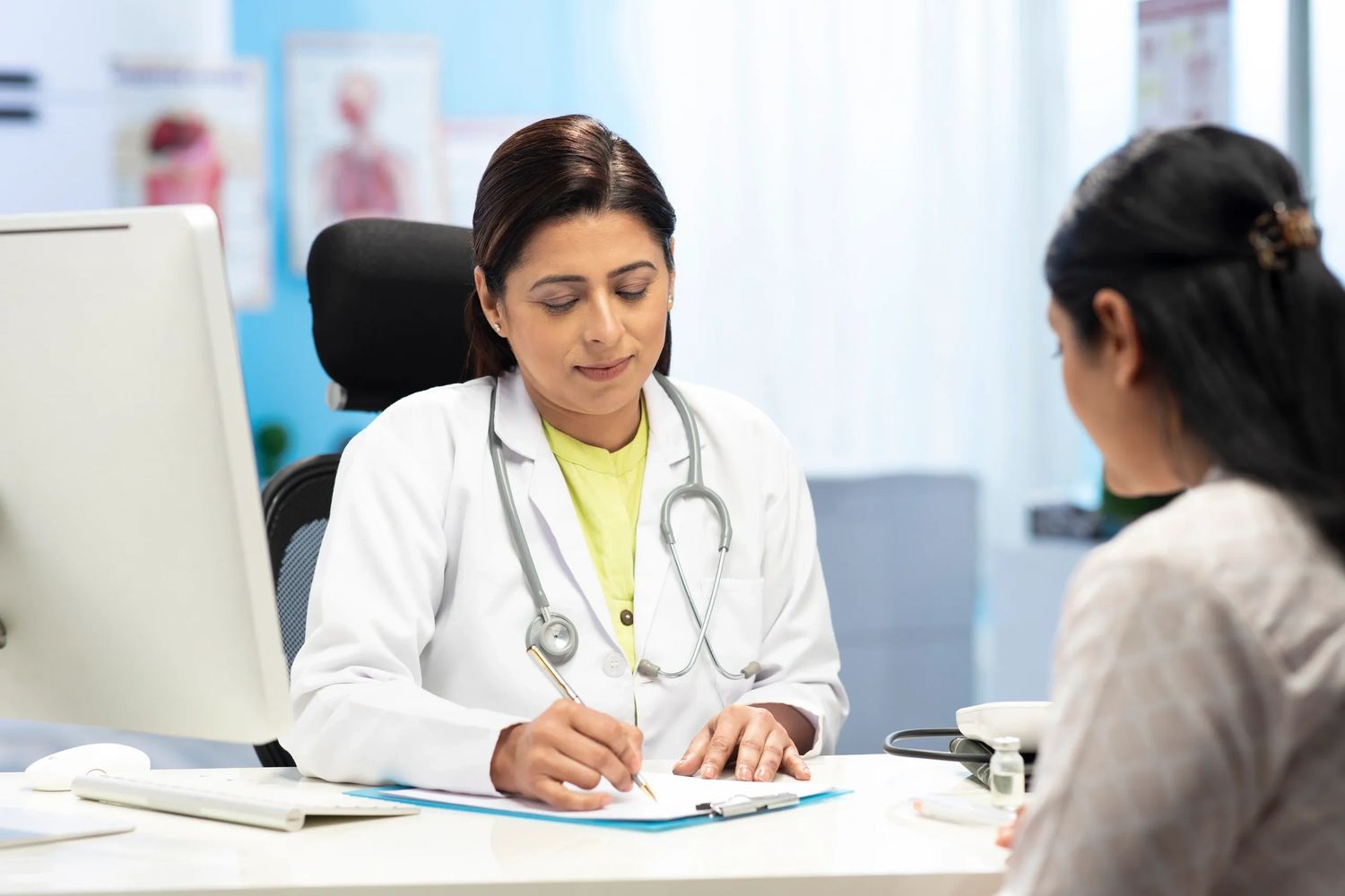 Female doctor writing notes during a patient consultation.