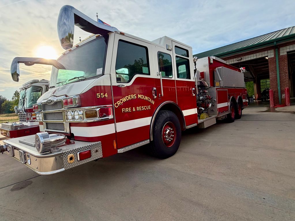 Red and white Crowders Mountain fire truck parked outside a fire station.