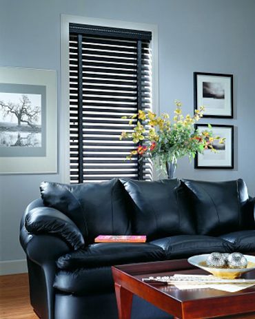 A window blind behind a black couch