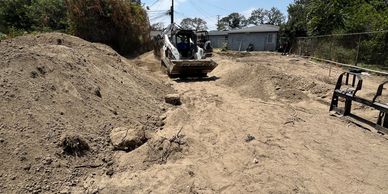 Construction site with excavated dirt and machinery under a clear sky.
