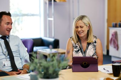 Two colleagues having a cheerful meeting around a table with a tablet.