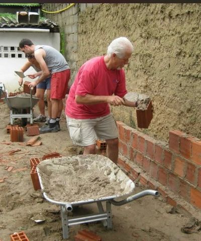 Two men building a brick wall outdoors.