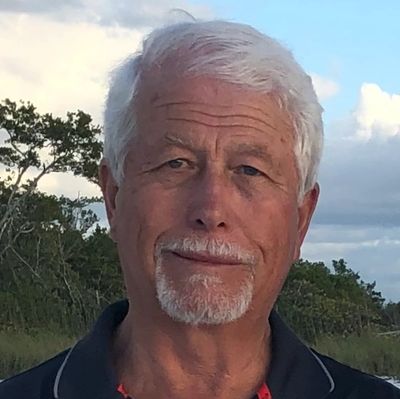 Older man with white hair and beard outdoors.