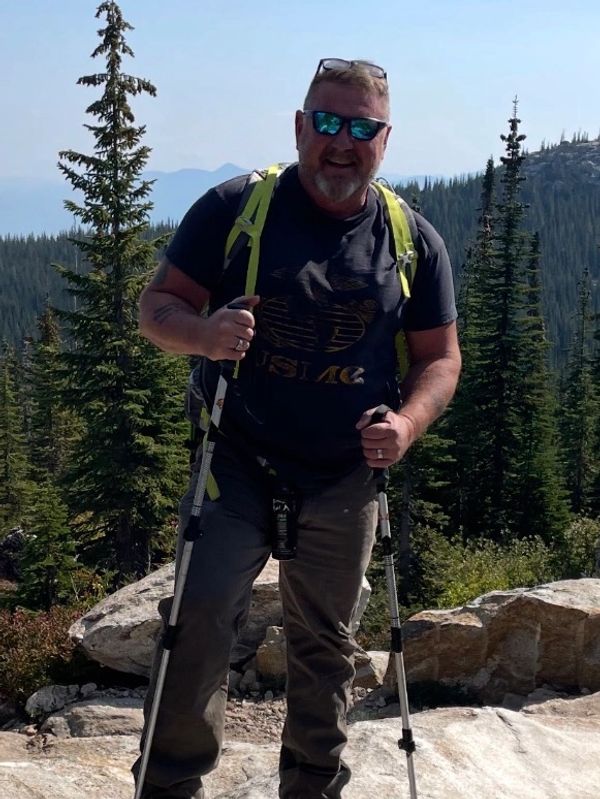 Man hiking with poles in a forested mountain area.