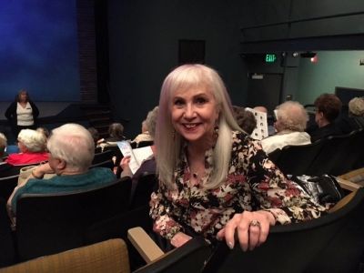 Smiling elderly woman in a theater audience.