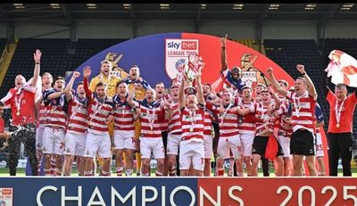 Football team celebrating their 2025 championship victory on stage.