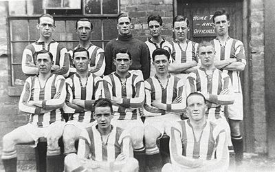 Black and white photo of a vintage football team posing outdoors.