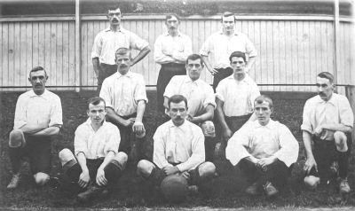 Black and white photo of a vintage men's sports team posing outdoors.