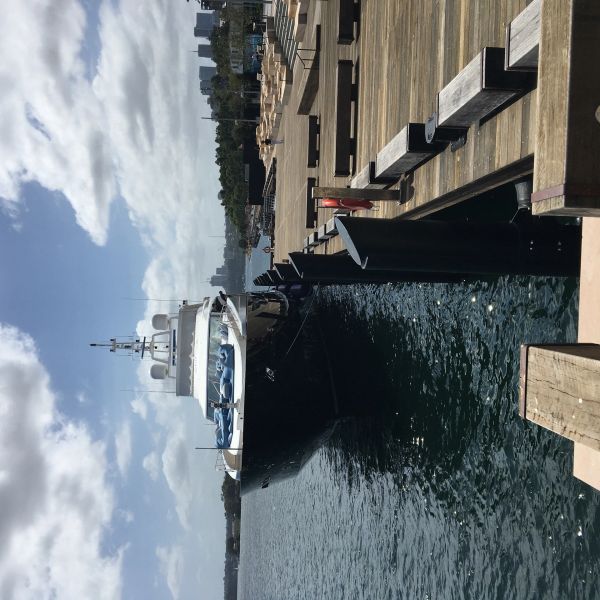 A luxury yacht docked at a wooden pier on a sunny day.
