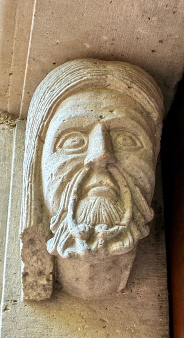 Ancient stone carving of a bearded man's head.