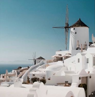 Traditional white buildings and windmills on a sunny day.
