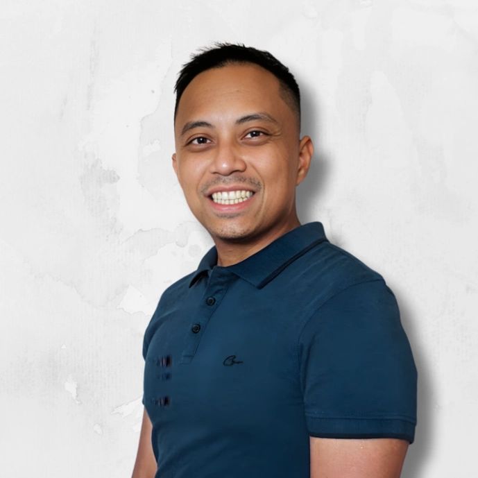 Smiling man in a navy blue polo shirt against a light textured background.