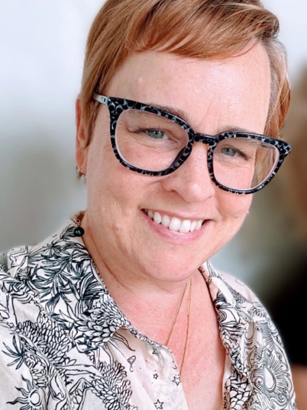 Amy Bates-Nelson Smiling with Black Glasses On
