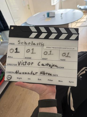 Hand holding a film clapperboard with production details.