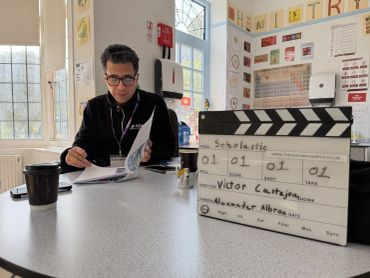Man reading script behind film slate on table.