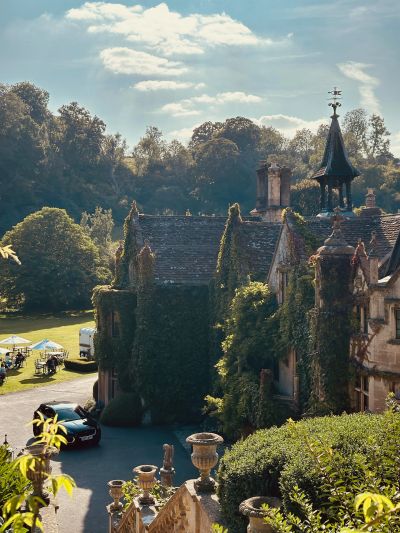 Old ivy-covered stone mansion with lush greenery.