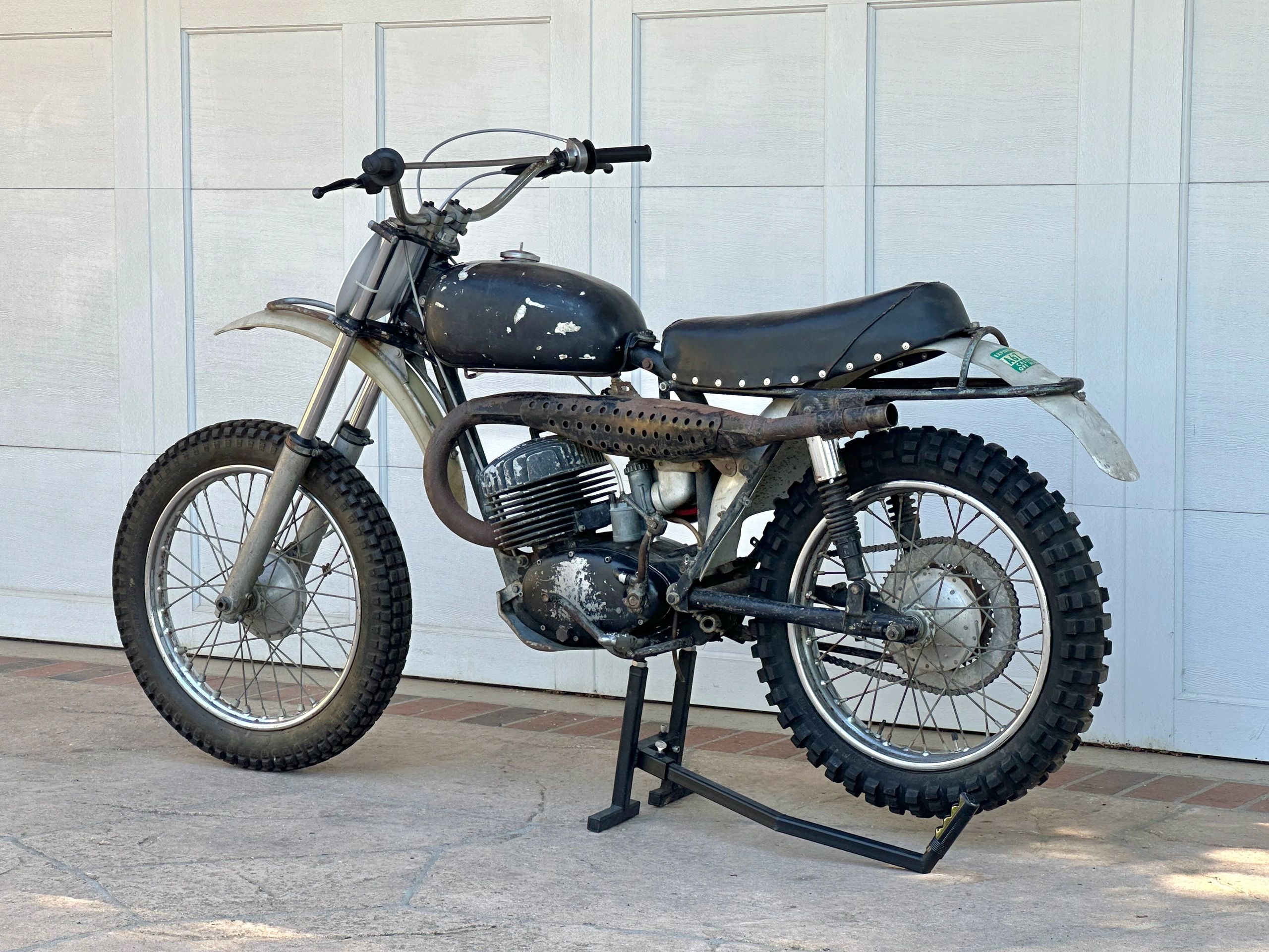 Vintage dirt bike with knobby tires and a worn black seat.