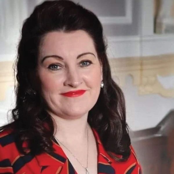 Smiling woman with dark hair and bright red lipstick.