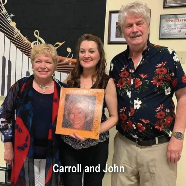 Three people posing, one holding a framed photo of a woman.