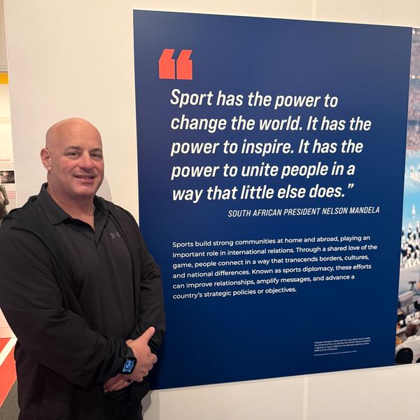 Man standing next to a Nelson Mandela sports quote poster.