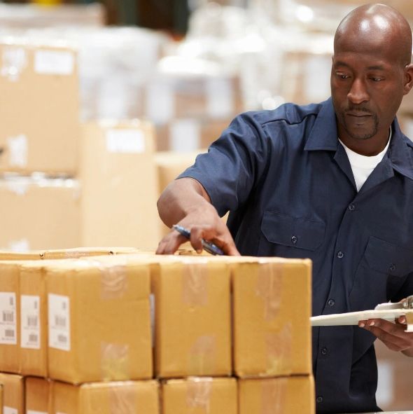 man in a warehouse checking a clipboard with boxes, supply chain economics, trading depots