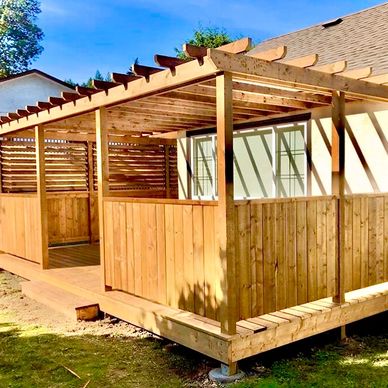 Newly built wooden pergola attached to a house with natural wood finish.