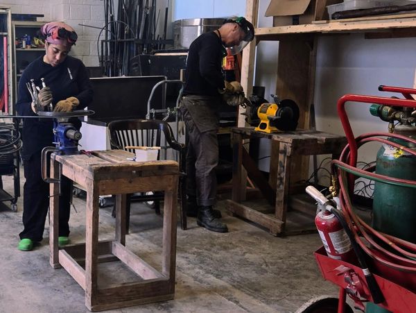 Two people working with tools in a workshop.