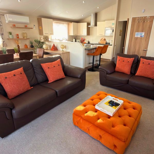 Modern living room with brown sofas and vibrant orange accents.