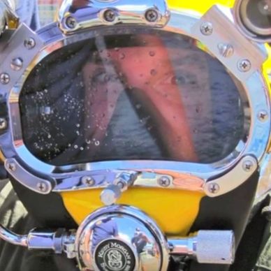 Reflection of a person in a diving helmet's glass.