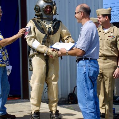 Person in vintage diving suit shaking hands during a ceremony.