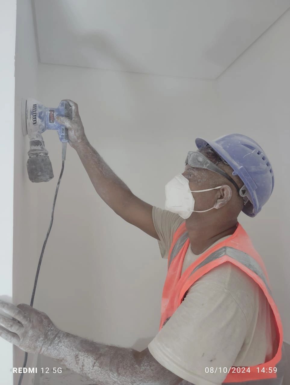 Sanding the wall using electrical sanding machine 