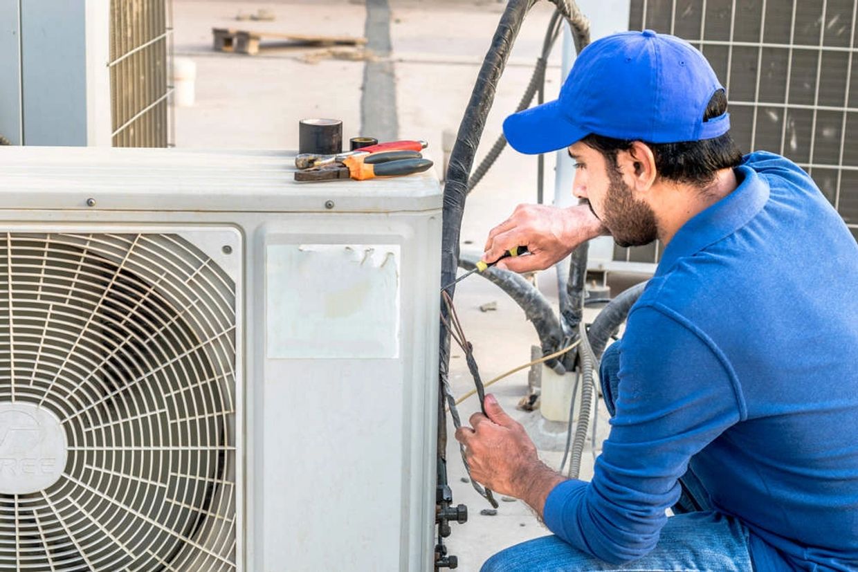 Man fixing an AC on the roof in Dubai