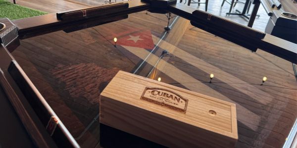 A Cuban cigar box on a glass table with a Cuban flag reflection.