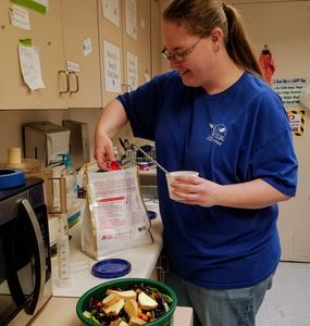 Woman preparing food in a kitchen while smiling.