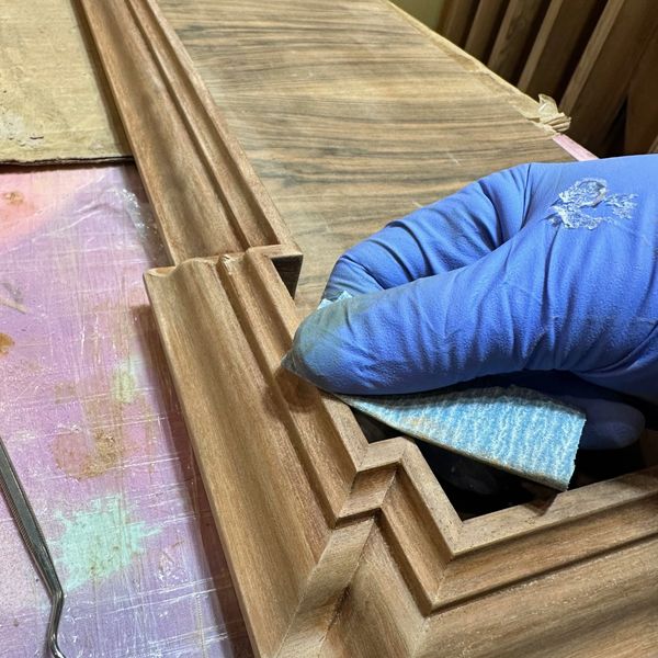 Hand Sanding an intricate wooden moulding. 