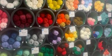 Colorful yarn balls organized in circular bins on a wall.