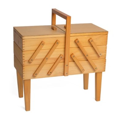 Wooden sewing box with multiple compartments and a handle on legs.