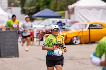 Young runner wearing a colorful shirt and cap in a race event.