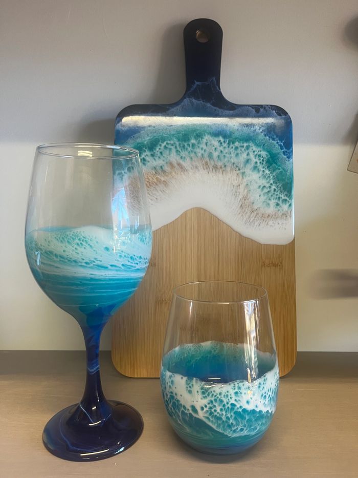 Two ocean-themed glasses and a matching wooden cutting board with wave designs.