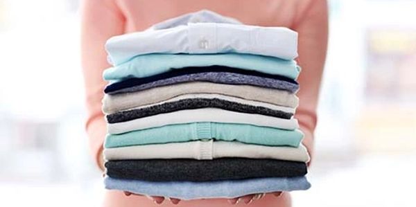The woman is presenting the stacked and folded wash and fold order.