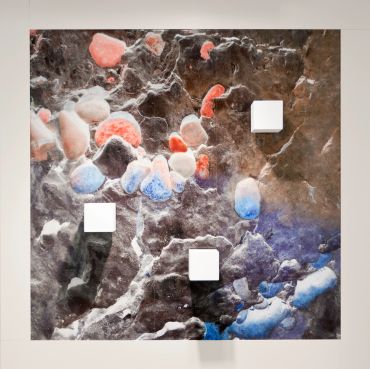 Abstract textured artwork with red, blue, and white elements on a dark background.