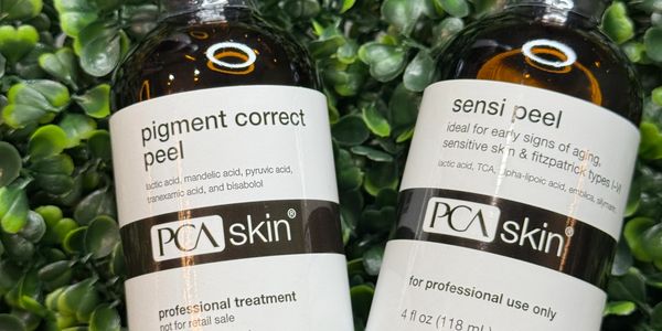 Two PCA Skin peel bottles on green leaves.