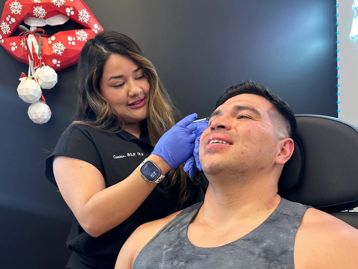 A woman giving a cosmetic treatment to a man.